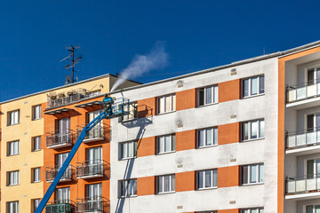 worker with high pressure washer cleaning house facade
