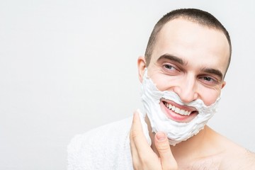 Smiling young man use shaving foam, white background, copy space