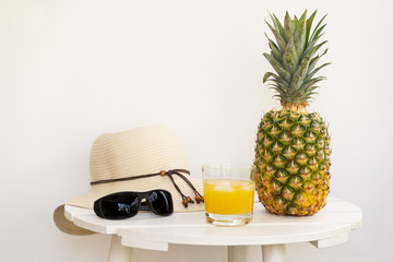 Whole Pineapple, Pineapple Juice, Sun Hat and Sunglasses on White Wood Table with White Background