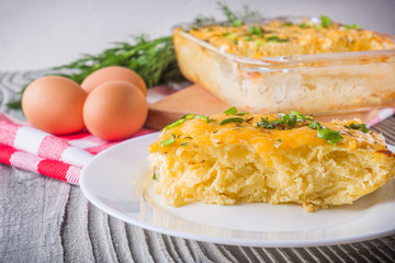 Delicious potato casserole with egg and cheese on a gray wooden background