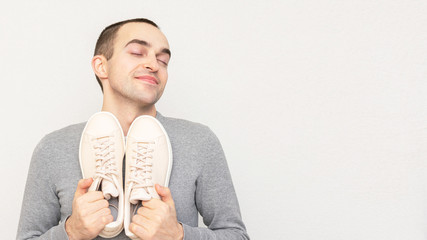 Happy man likes to play sports, man shows off with his sneakers, portrait, close-up, copy space, 16:9