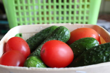fresh tomatoes and cucumbers in a wooden basket in the home kitchen 