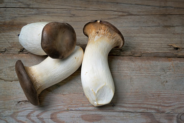 Fresh king oyster mushrooms, Pleurotus eryngii, on rustic wooden planks, copy space, high angle view from above