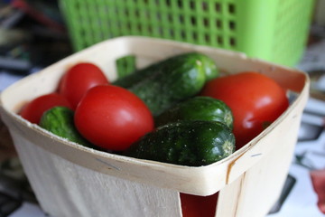 fresh tomatoes and cucumbers in a wooden basket in the home kitchen 
