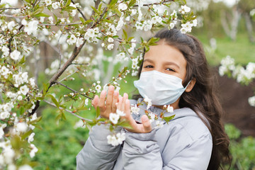 Little girl with brown hair wearing facial mask for virus protection.