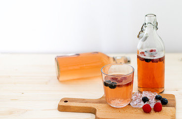 Homemade fermented kombucha fruit tea in glass bottles with ices and berries. Probiotic, gut...