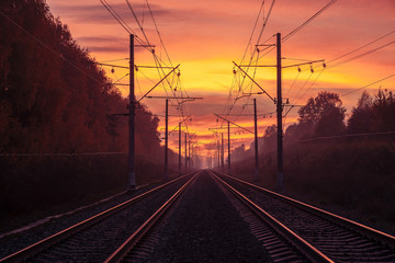 Obraz na płótnie Canvas Rails extending into the distance, illuminated by the sunset sky.