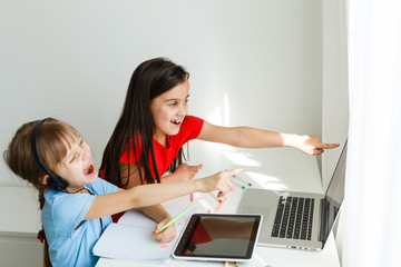 Cool online school. Kids studying online at home using a laptop. Cheerful young little girls using...