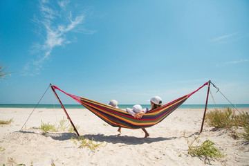 Children have a rest in a hammock on a sandy seashore