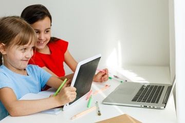 Pretty stylish schoolgirls studying during her online lesson at home, social distance during quarantine, self-isolation, online education concept