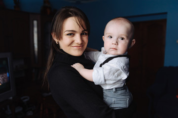 Young smiling mother holding little son in her arms