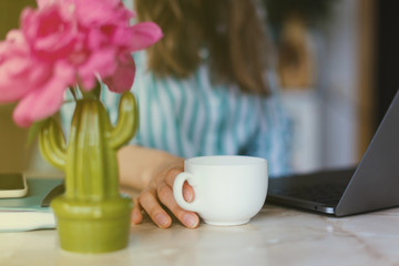 photo of woman hands holding cup of coffee while working at lap