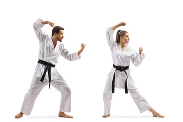 Full length shot of a young man and woman with black belts practicing karate