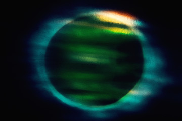 Abstract dirty-grass-colored circle-shaped moon-like background with a blue halo on a black background. Beautiful mysterious background for design.