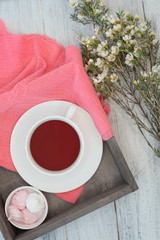 Morning tea party in spring. Cup of tea with marshmallows and a bouquet of flowers and a coral napkin on a white wooden background.