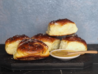 Homemade cake.The view on top of buns ,sprinkle with sesame seeds and sugar syrup on the dark table.