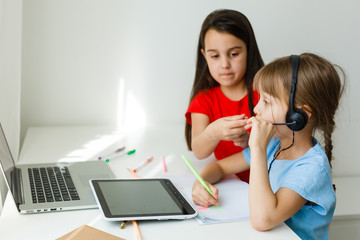 Cool online school. Kids studying online at home using a laptop. Cheerful young little girls using...