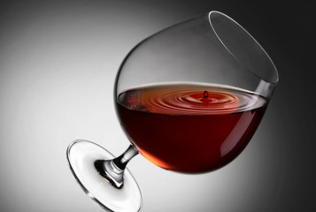 cognac in a glass with splashes on a gray background close up