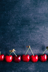Cerises avec leurs queues alignées sur un fond foncé - Arrière plan design alimentaire