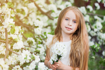 Obraz na płótnie Canvas Beautiful preteen girl with long blond hair enjoy spring apple blooming. Little preschool girl in garden tree flowers. Copy space for text.