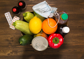 Donation in a box. 
First ai. In a cardboard box. The volunteer brought the products for people to self-isolation. Products on a background close-up, a place for an inscription. Products for the poor