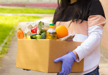Girl courier volunteer wearing holds a paper bag with products, vegan vegetables, quarantine,...