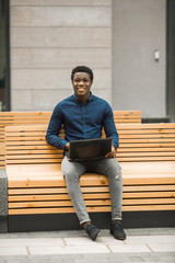handsome young african man sitting with laptop