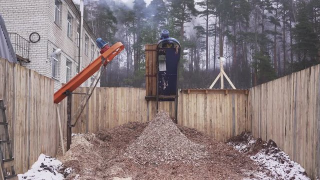 Wood sawdust fly out of the automatic machine for the production of sawdust. Steadycam shot