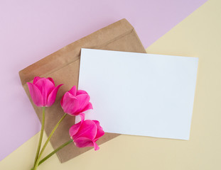 Pink tulips flowers flat lay and empty mock up letter with envelope on pastel paper double pink vanilla background. Creative minimal spring or summer festive concept, top view, copy space