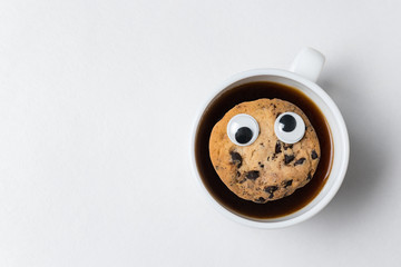 Cookies with Googly eyes floating in Cup of tea. Coffee Cup with cookies on white background, top view