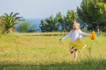 Little girl running on green grass. Summertime fun.