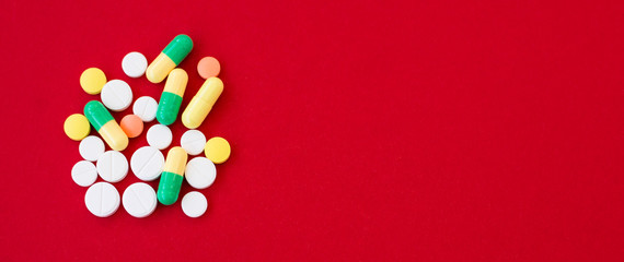 Fototapeta na wymiar Medical background with pills and capsule on red background.Assorted pharmaceutical medicine pills, tablet. Heap of various assorted medicine tablets and pills different colors. Health care. Top view