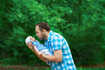 Naklejka na ściany i meble Dad keeps the baby in nature. A father wants to kiss his little son.