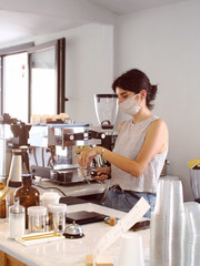 young barista girl in medical mask with city cafe background