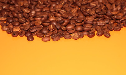 Coffee beans on a bright background. Coffee granules on an orange table. Texture of coffee beans.