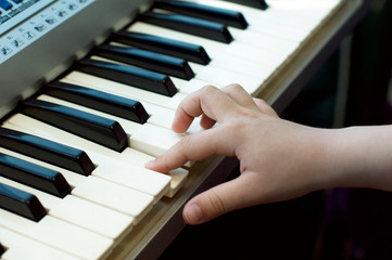 Fototapeta na wymiar Child's hand playing synthesizer keys