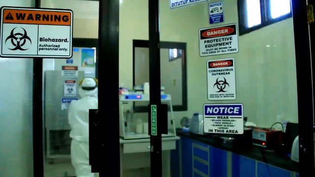 man wearing hazmat works at covid-19 diagnosis laboratory