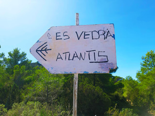 rudimentary road signs sign indicate the way to Es Vedra and to Atlantis among the green trees and the vegetation of ibiza