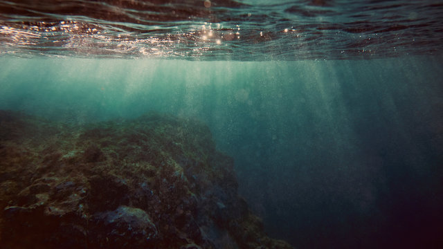 View underwater of waves breaking over rocks