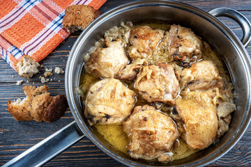 Appetizing tasty fried chicken thighs in a pan on wooden boards, top view, rustic style. Homemade food concept.