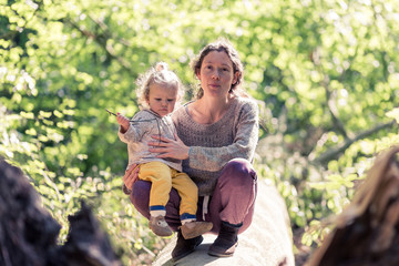 Fototapeta premium mère et fille sur un tronc d'arbre dans la forêt