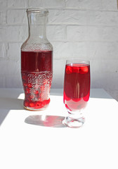 A glass of red compote. Cherry compote in a decanter next to a glass