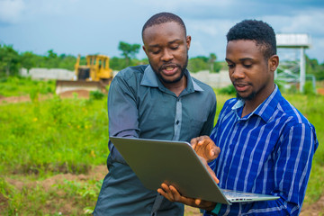 young black men discussing some business plans to be executed on a farmland