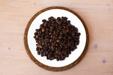 coffee beans on a white plate and cork stand background