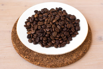 coffee beans on a white plate and cork stand background