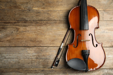 Beautiful violin and bow on wooden table, top view. Space for text