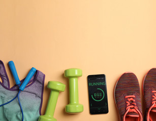 Flat lay composition with fitness equipment and smartphone on orange background. Space for text