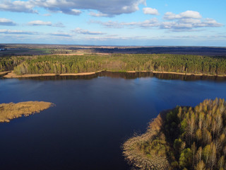 Aerial shot of storage reservoir. Landscape with blue sky and white clouds, flat terrain, river, forest, top view.