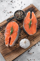 Fresh steaks of red salmon fish with spices and herbs on a wooden board. Healthy food.