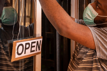 a local african business owner putting up a open sign in front of his store